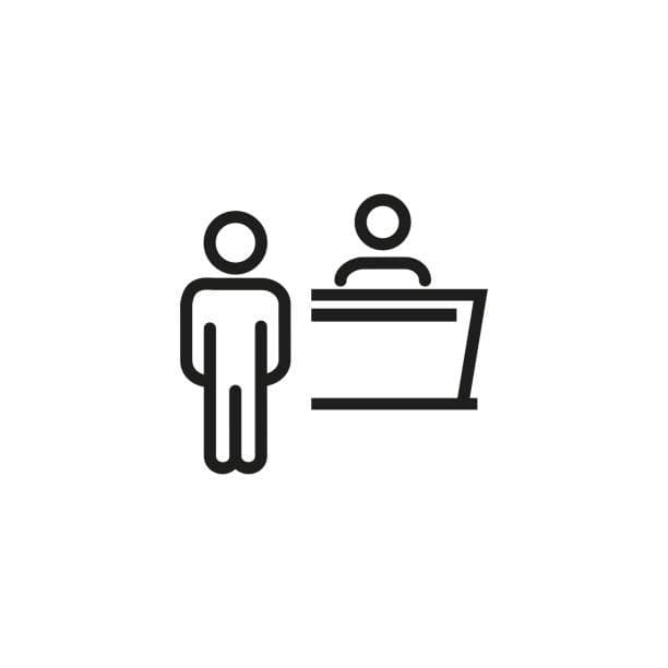 Icon of a person standing in front of a reception desk with a staff member behind it.